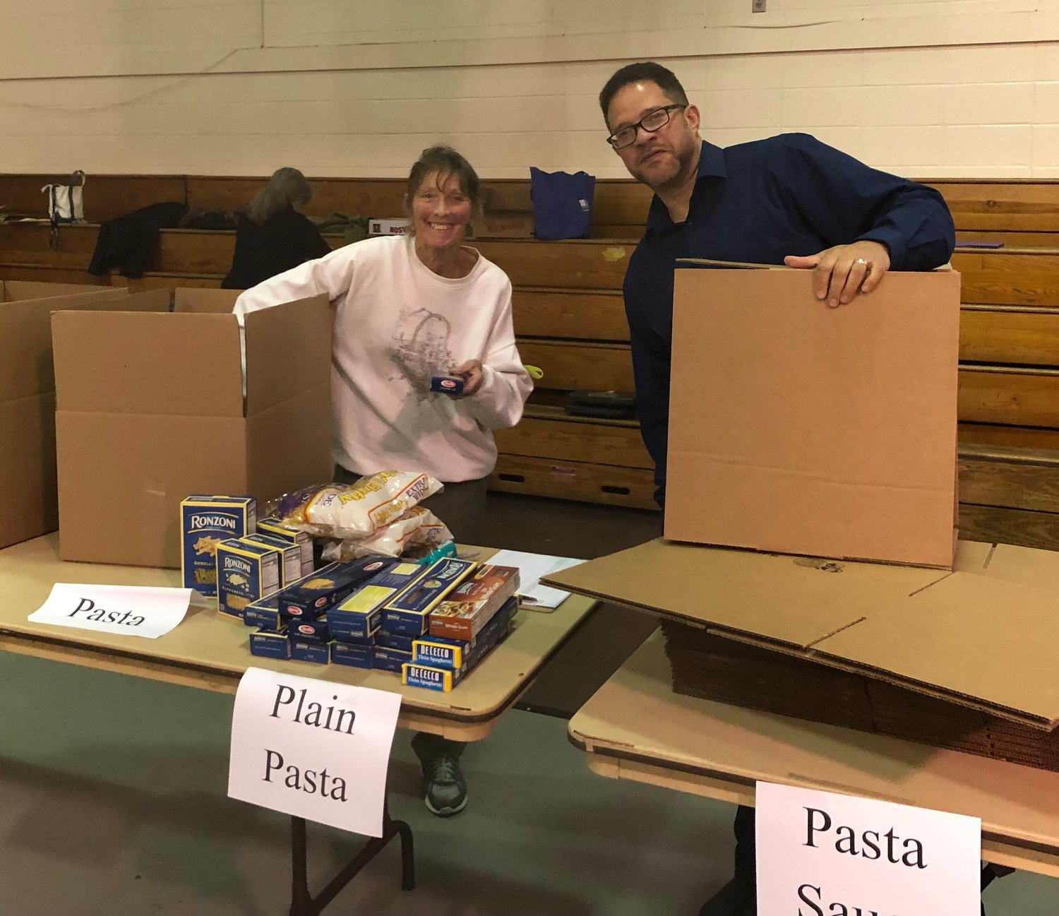 Volunteer Pat Schiskie, left, and Catholic Charities Director of Social and Human Services Hector Morell help sort and pack donated food items.