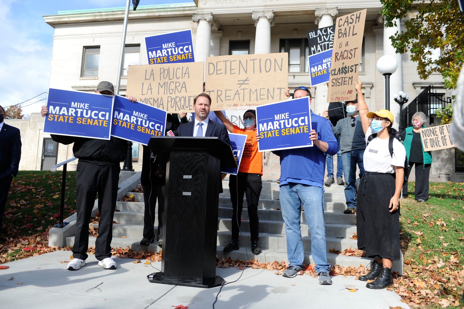 Sign wars. NYS Senate Republican Leader Ron Ortt addresses the small crowd, flanked by signs of protest and in support of senatorial candidate Mike Martucci.