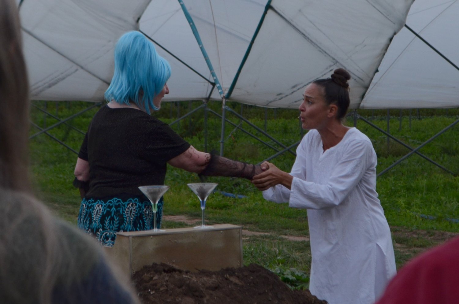 Cilly the Microbe (played by Annie Hat, left) meets with Lynn Margulis (played by Jess Beveridge) over drinks at a compost party.