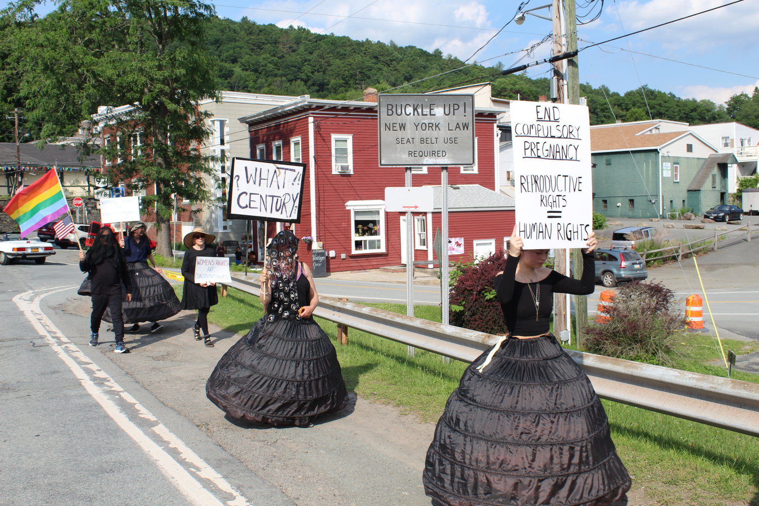 Clad in black, some wearing black hoop skirts, men, women and a child walked up and down the Callicoon bridge.