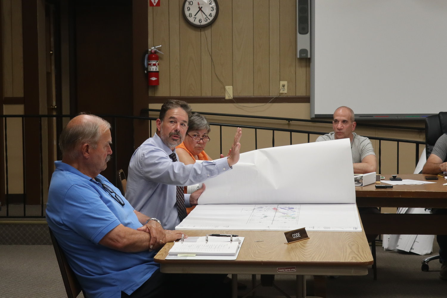 Engineer Ken Ellsworth, center with stack of plannning maps, asks a few clarifying questions at the July 27 Highland Planning Board meeting. He is flanked by code officer Jim Hansen and planning secretary Monica McGil.